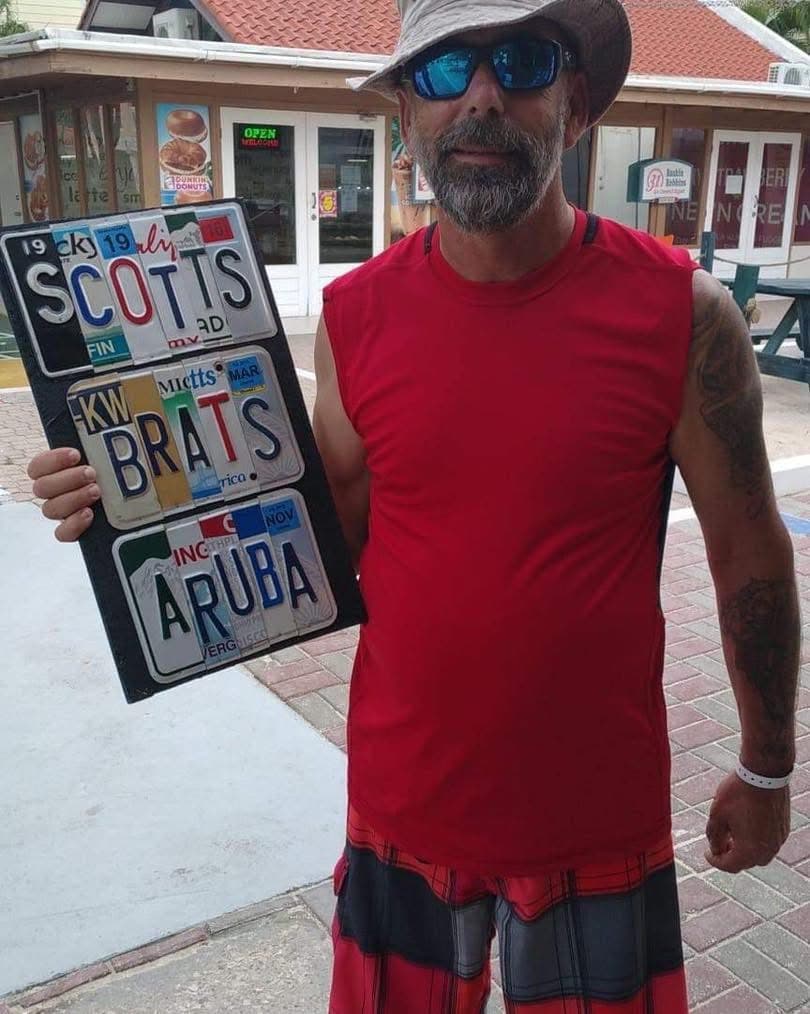Customer holding Scotts Brats Aruba custom license plate sign
